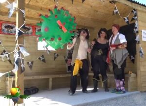 Three people dressed as pirates looking at green ball symbolising a virus.