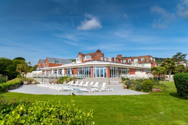 A large, low building, with lots of large glass windows looking out onto a sun terrace