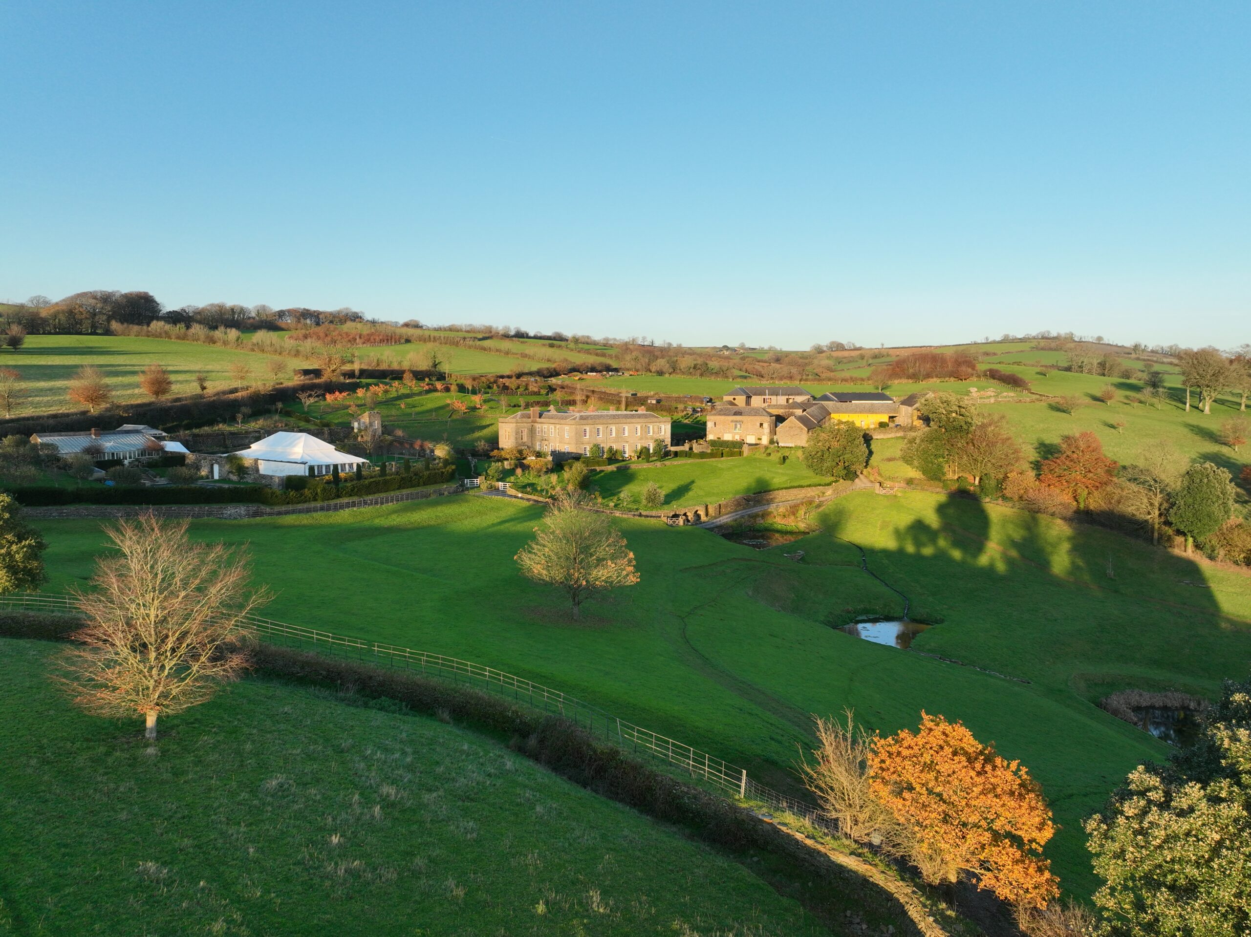 An aerial shot of a large building and grounds, surrounded by fields and trees