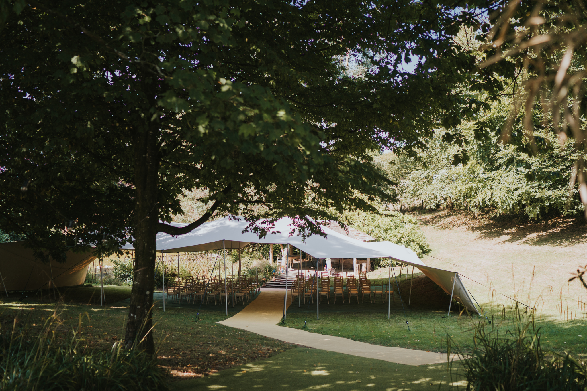 A marquee set amongst trees with seating inside
