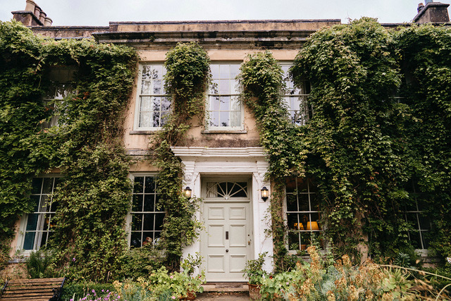 The front of Ambrook House, with ivy plants covering the building and a large white entrance door.