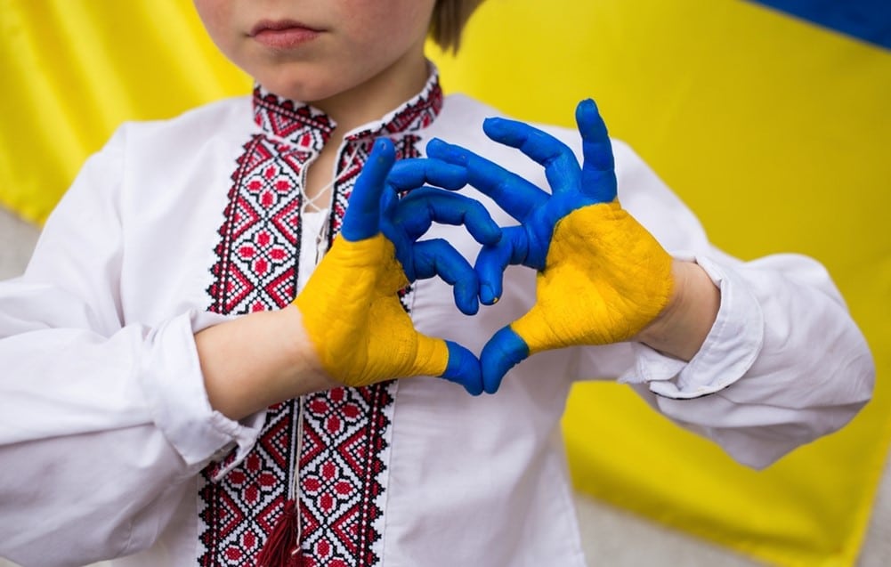 Child showing Ukraine flag with their hands