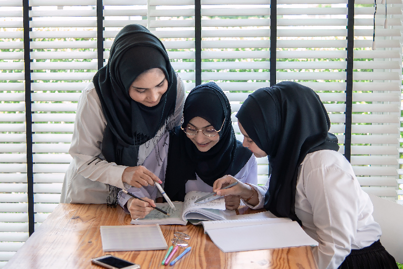 Three children in hijabs studying