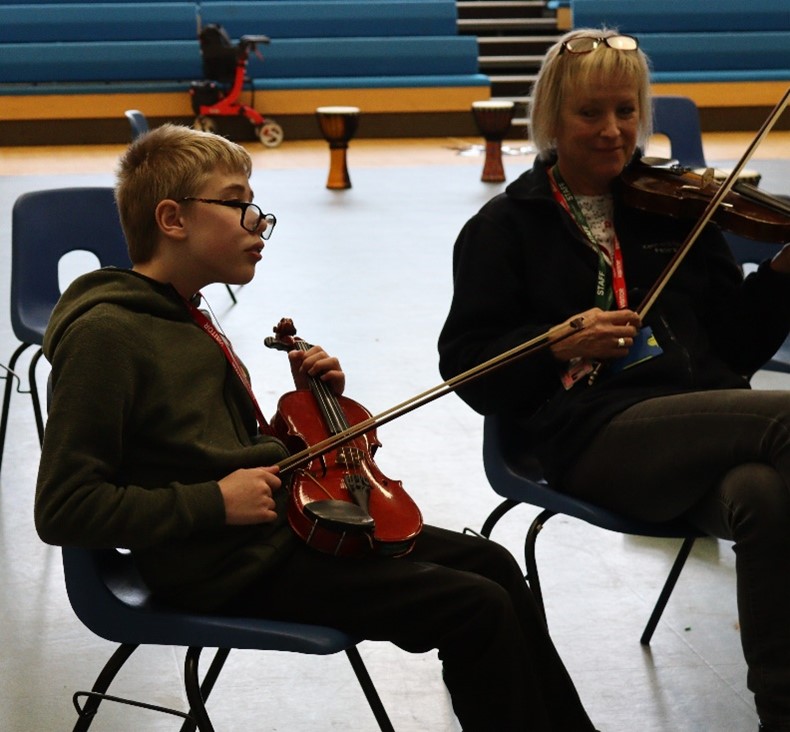 Child with adult playing a violin