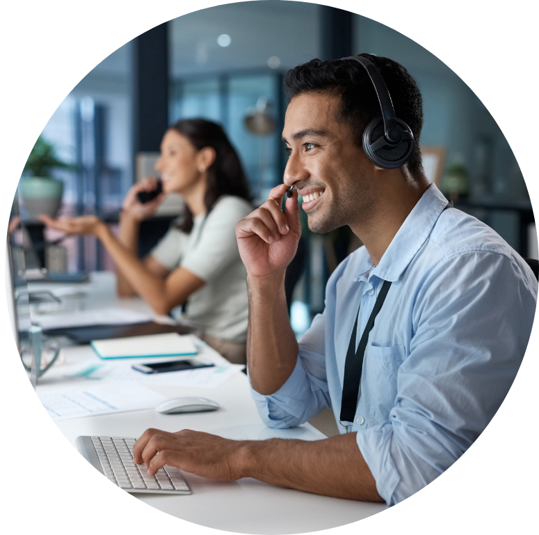 Round picture of two people working at a desk with laptops (off shot) in front of them, and wearing head phones.