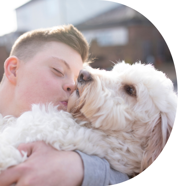 child with down syndrome cuddling and kissing a dog