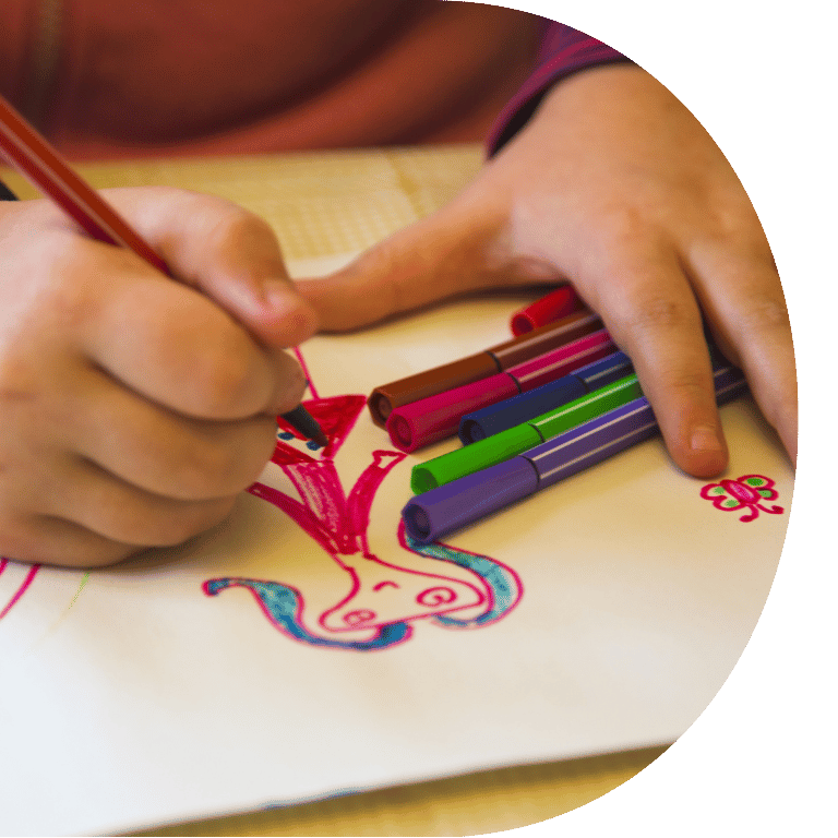 Image is cropped to a D shape and shows a close up of a child colouring in a bright drawing.