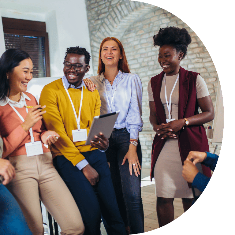 The image is cropped to a D shape and shows an ethnically diverse group of adults gathered around laughing.
