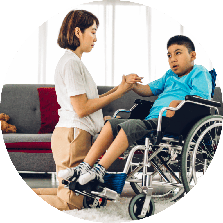 The image is cropped to a circle and shows a woman kneeling down holding hands with a disabled child in a wheelchair.