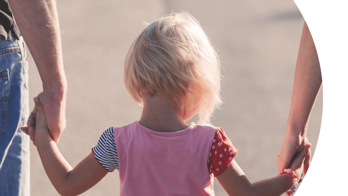 shows a child in the middle, with an adult both sides holding their hand.