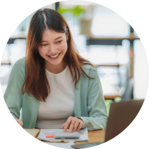 The image is cropped in a circle and shows a person in front of a laptop using a calculator.
