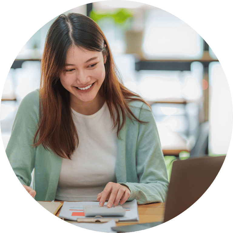 The image is cropped in a circle and shows a person in front of a laptop using a calculator.