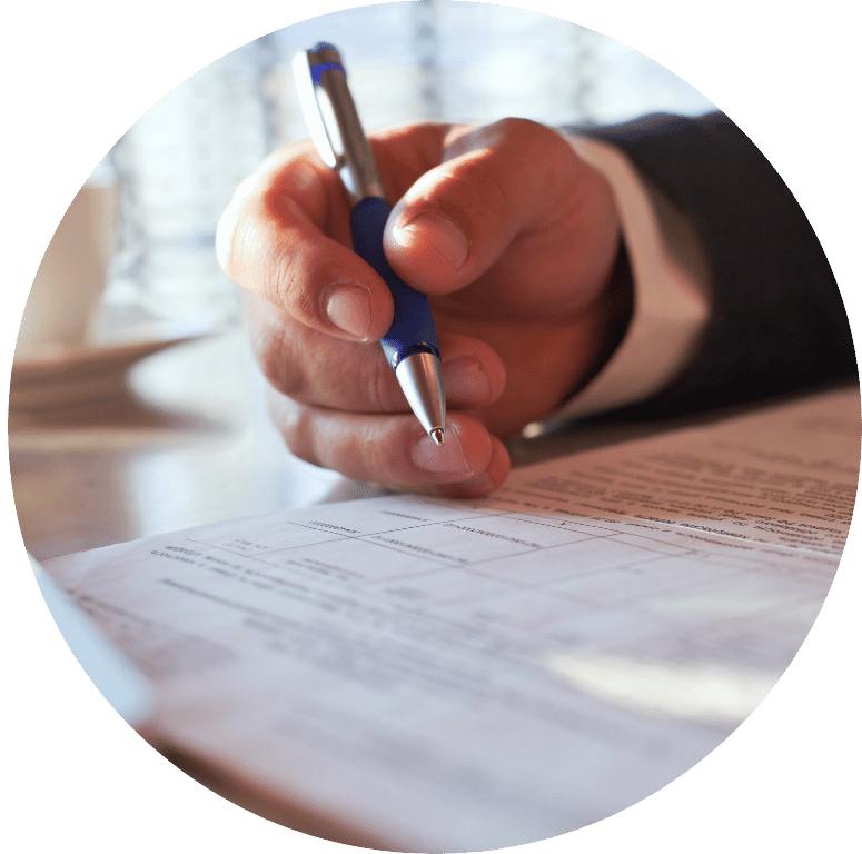 Picture of a hand holding a pen, signing a document.