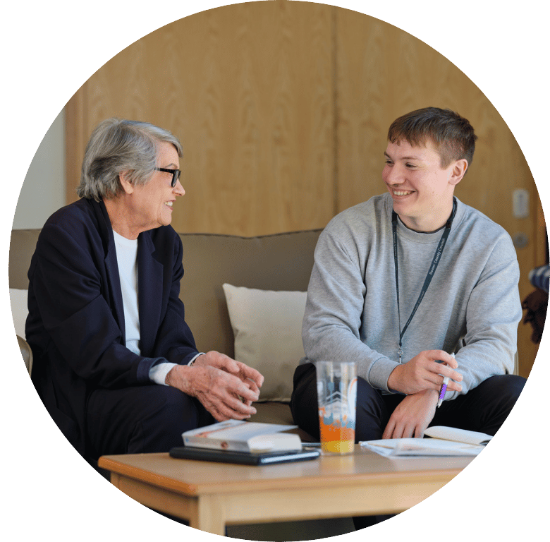 Picture of two adults sat on a sofa talking.
