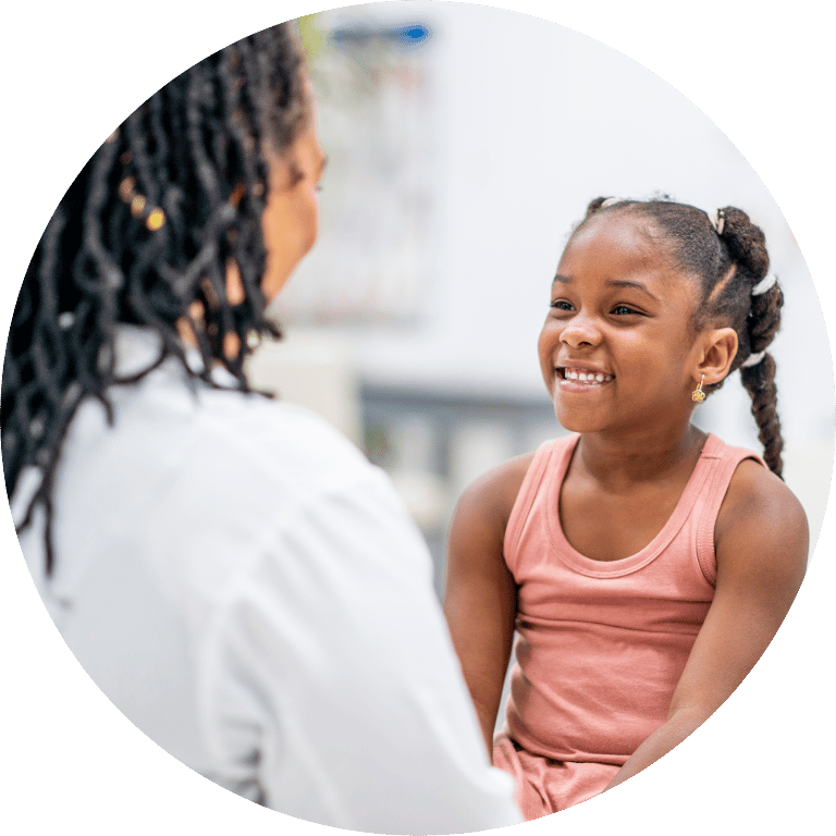 The image is cropped in a circle and shows child smiling at a nurse.