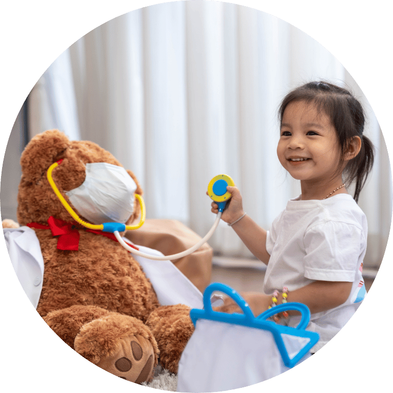 Image is cropped to a circle and shows a young girl with a doctor pretending to be a doctor