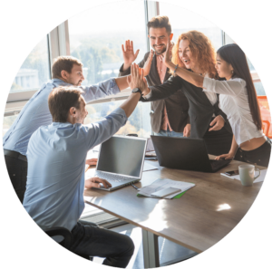Picture of five people in a meeting environment. They are happily doing a high five across the table.