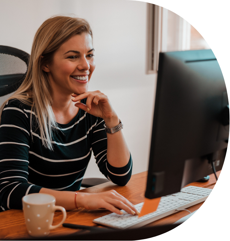 A person sat at a desk, smiling and looking at the screen.