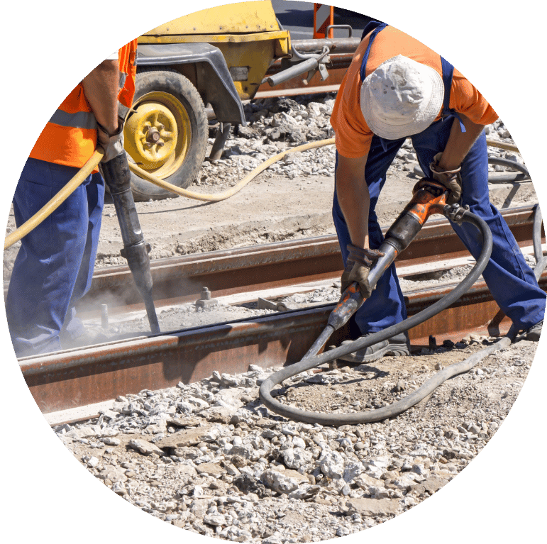 Image is cropped to a circle and shows 2 construction workers working on railway tracks.