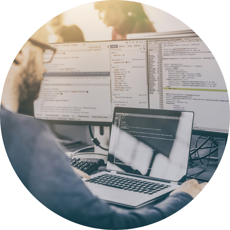 The image is cropped in a circle and shows the back of someone working on a laptop