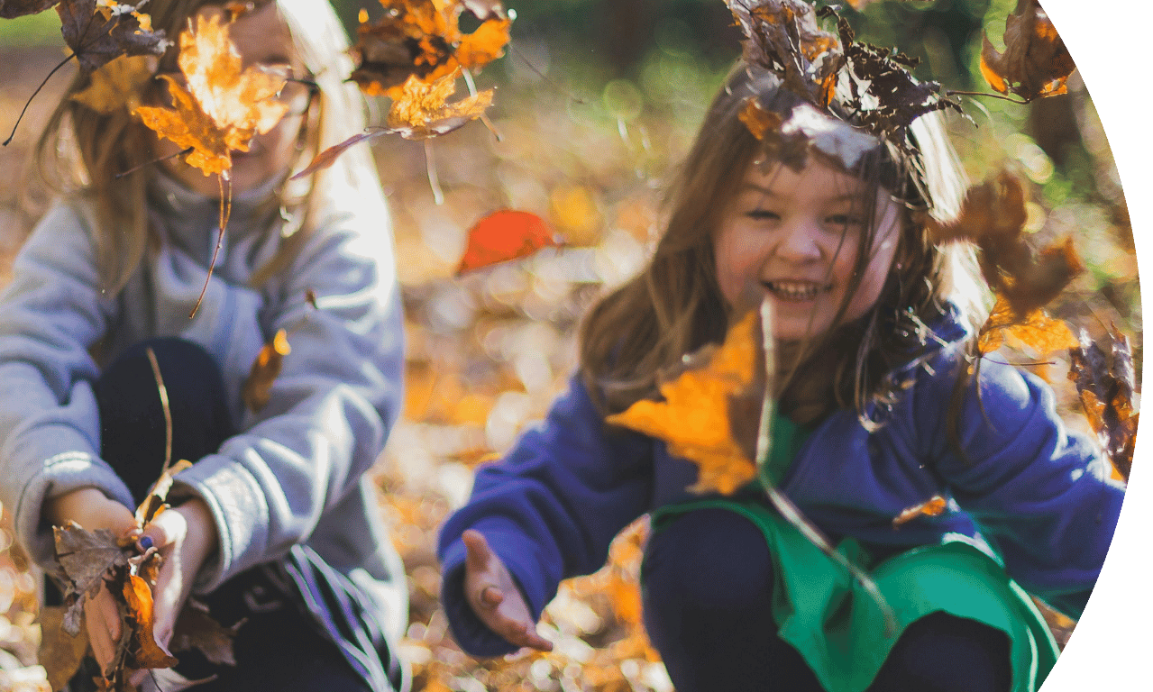 Two children playing in the Autumn leaves