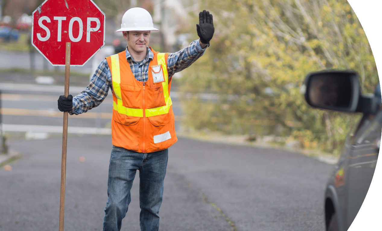 Person with high vis jacket and stop sign standing in the road stopping traffic.