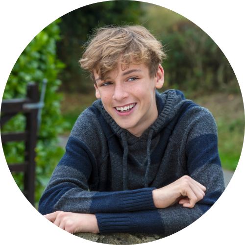 Young adult sat on a picnic bench with folded arms and smiling