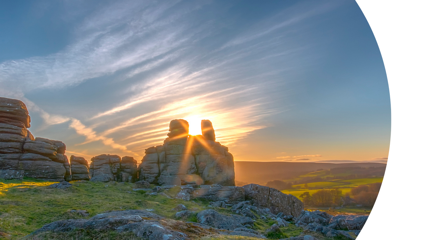 image shows rock formations on a moor, with a sunset in the background.