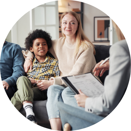 Image shows a smiling family sat on a sofa, with a support worker opposite with a clipboard