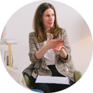 Image of a person sat looking off camera with a clipboard on their knee.