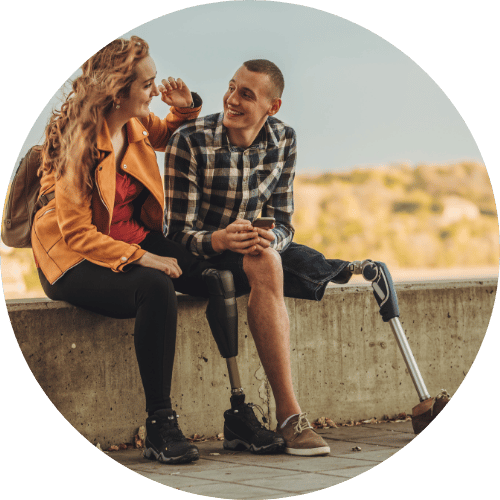 Two people sit on a sea wall.