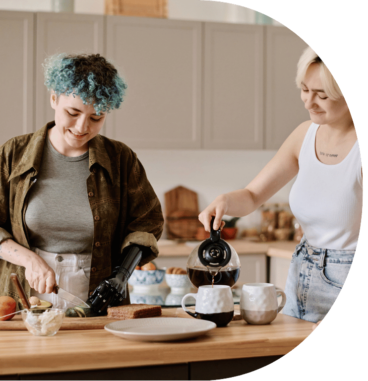 Two young adults making hot drinks together. One of them has a prosthetic arm