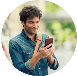 A person outside smiling at their phone in their hands.