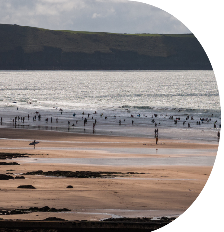 Silhouette of people, playing and relaxing on the shore of sea at Woolacombe beach, coastal lifestyle scene. Holiday on a beautiful North Devon coast.