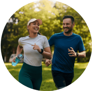 Two people jogging through a park together smiling.