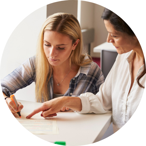 Picture of two adults sitting at a desk discussing the documents in front of them.