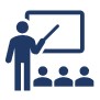 Teacher pointing at a whiteboard with students looking on