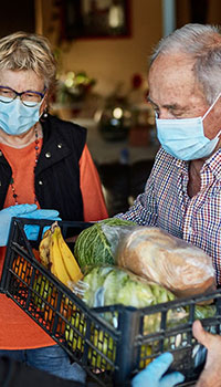 An elderly man carrying a box of food