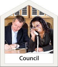 A man and a woman in a suits sat at desks with one on the telephone