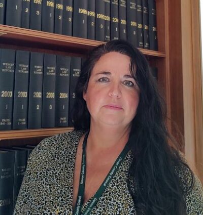 Maria Price, Director of Legal and Democratic Services, stood in front of a book case.